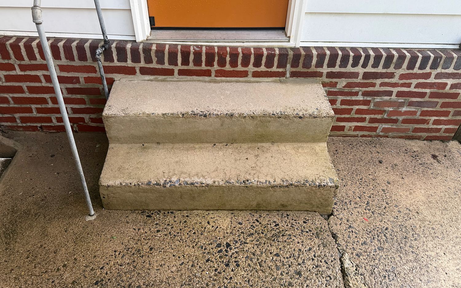 The same Lansdowne, PA front steps and walkway after pressure washing, the concrete back to a clean warm gray and the brick a deep red