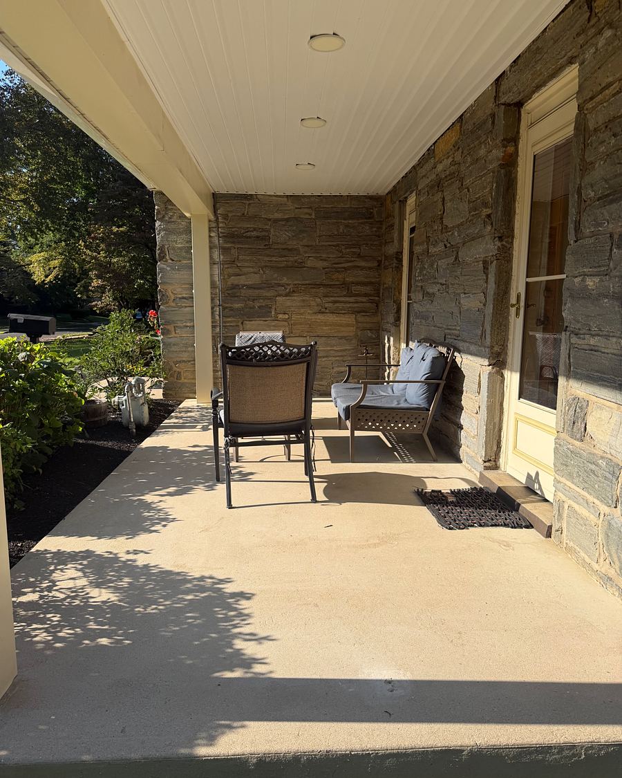 The same Drexel Hill, PA covered porch from the far end, clean concrete under the chairs and along the stone wall