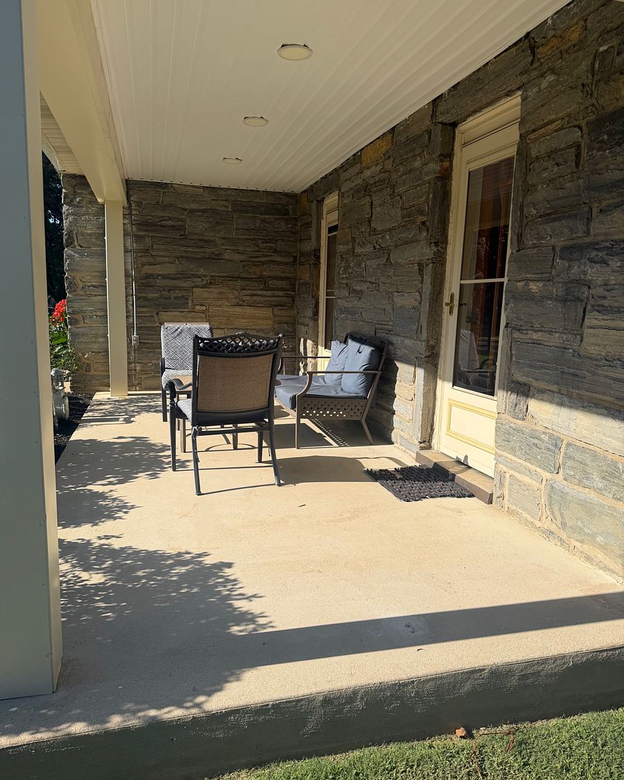 Covered front porch of a stone home in Drexel Hill, PA after washing, the concrete slab clean and the patio furniture back in place