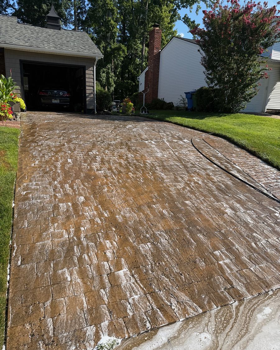 Stamped concrete driveway mid-wash, clean and dirty concrete divided in one frame