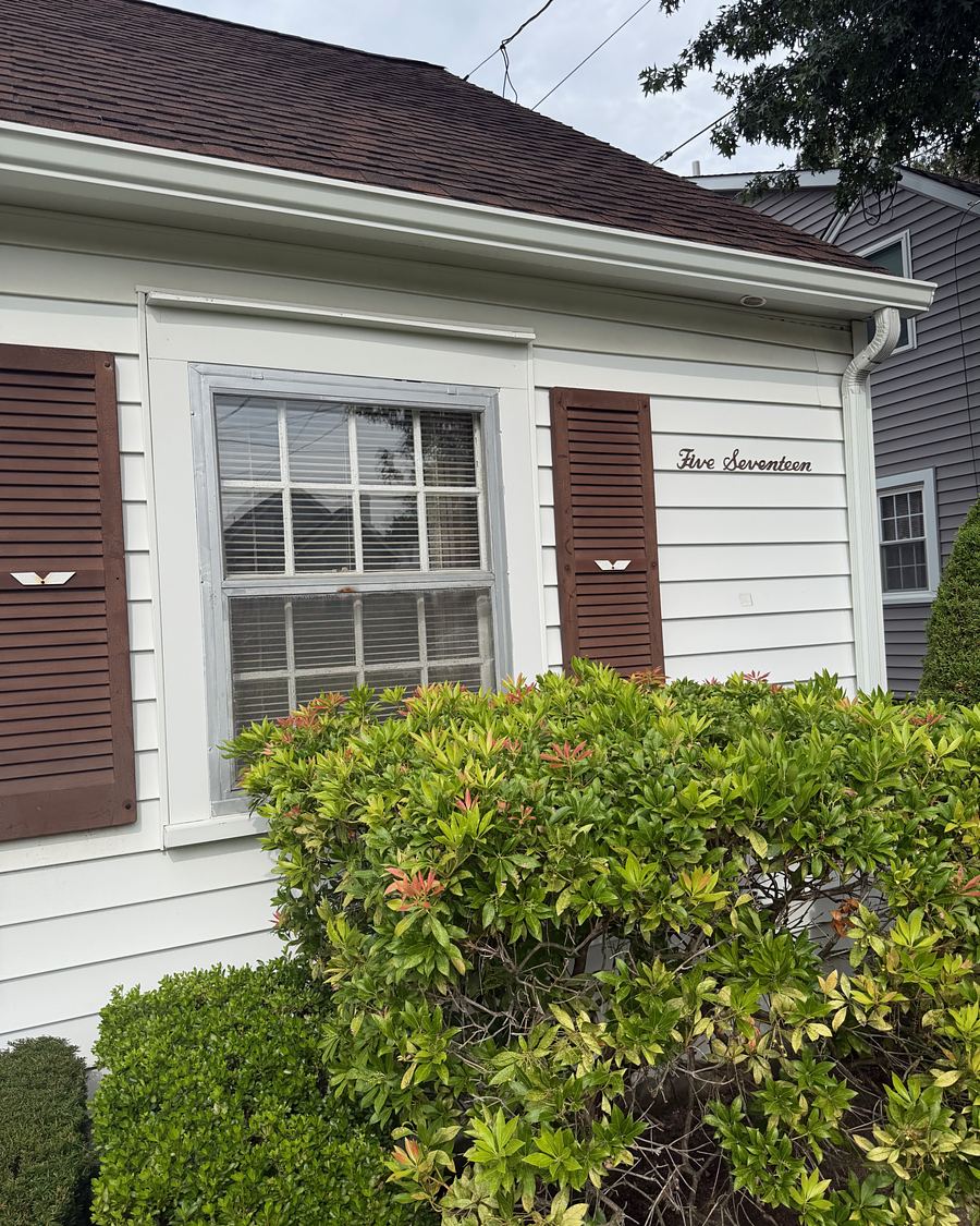 White clapboard cape with brown shutters and trimmed shrubs in Havertown, PA after gutter brightening
