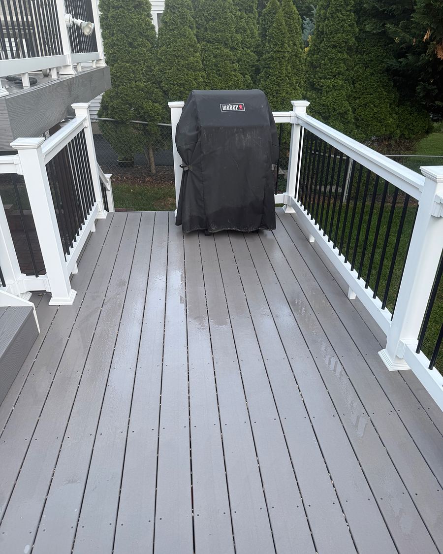 Composite deck with white railing after soft washing, boards clean and even