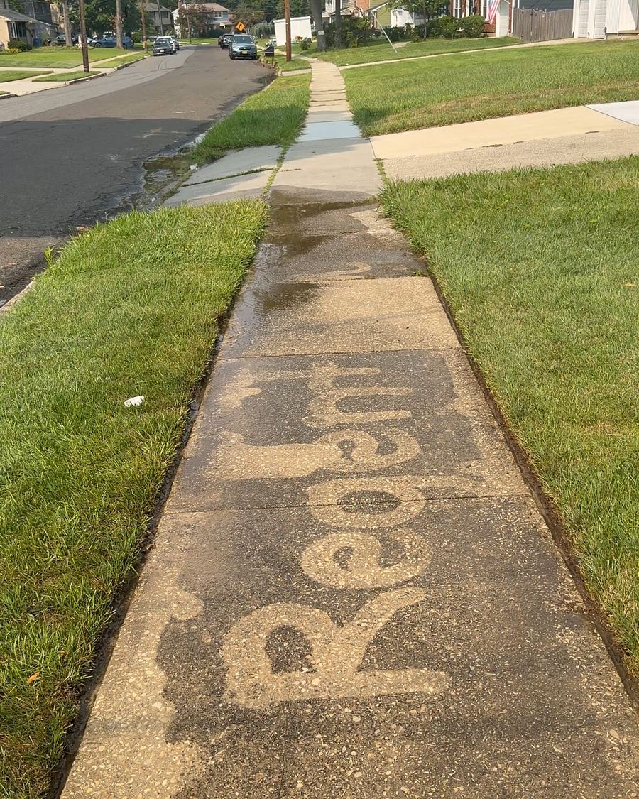 Concrete sidewalk being cleaned, with the word Regent washed into the untouched grime