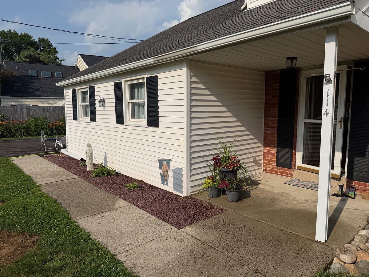 Washed white sided home in Hatboro, PA with black shutters, brick entry and a clean concrete walkway