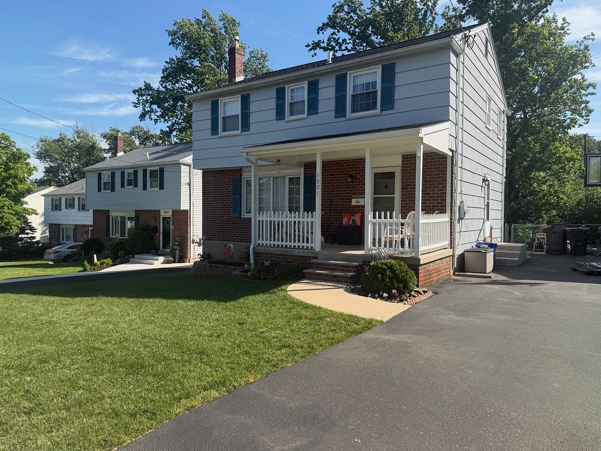 Freshly washed brick and blue siding twin home in Havertown, PA with a white picket porch rail