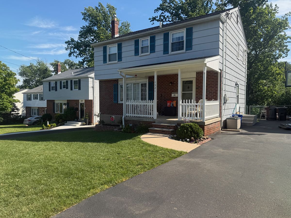 Brick and light blue twin home in Havertown, PA after washing, with a clean cream walkway curving to the porch
